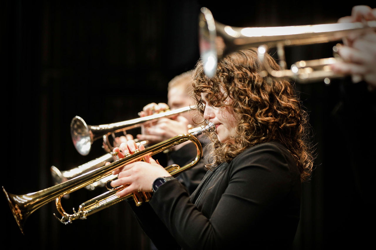 A female CCM Jazz Orchestra student plays the trumpet on the Patricia Corbett Auditorium stage.