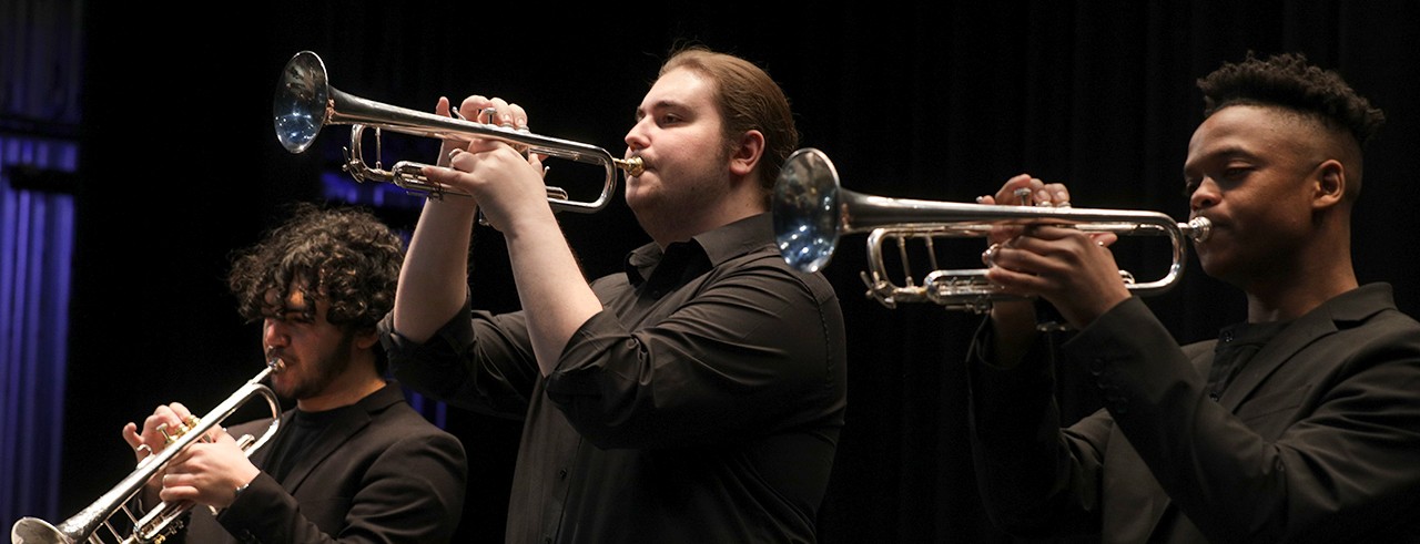 Three members of the Jazz Lab Band play trumpets on stage