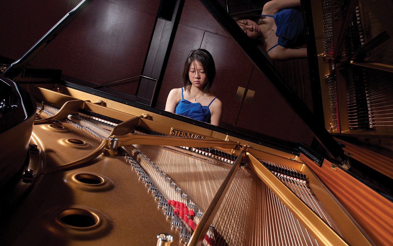 Piano student performs on Steinway piano with her reflection on the lid