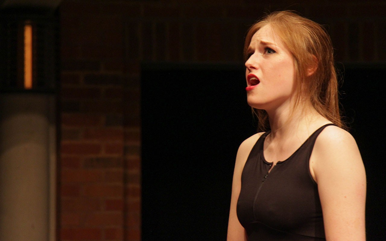 A student singing in a performance venue